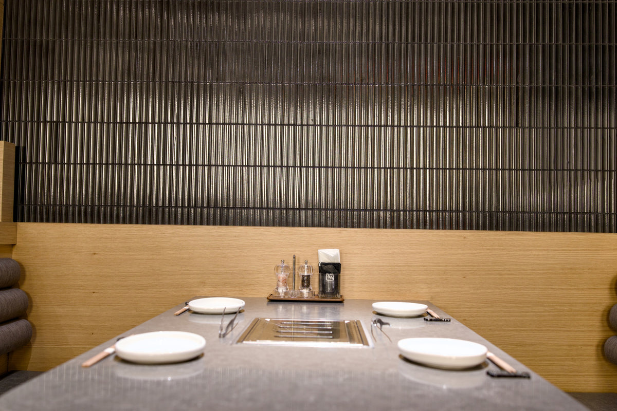 Timber dining booth against Yuki Border Speckled Black tiles at Gyu-Kaku Dubai