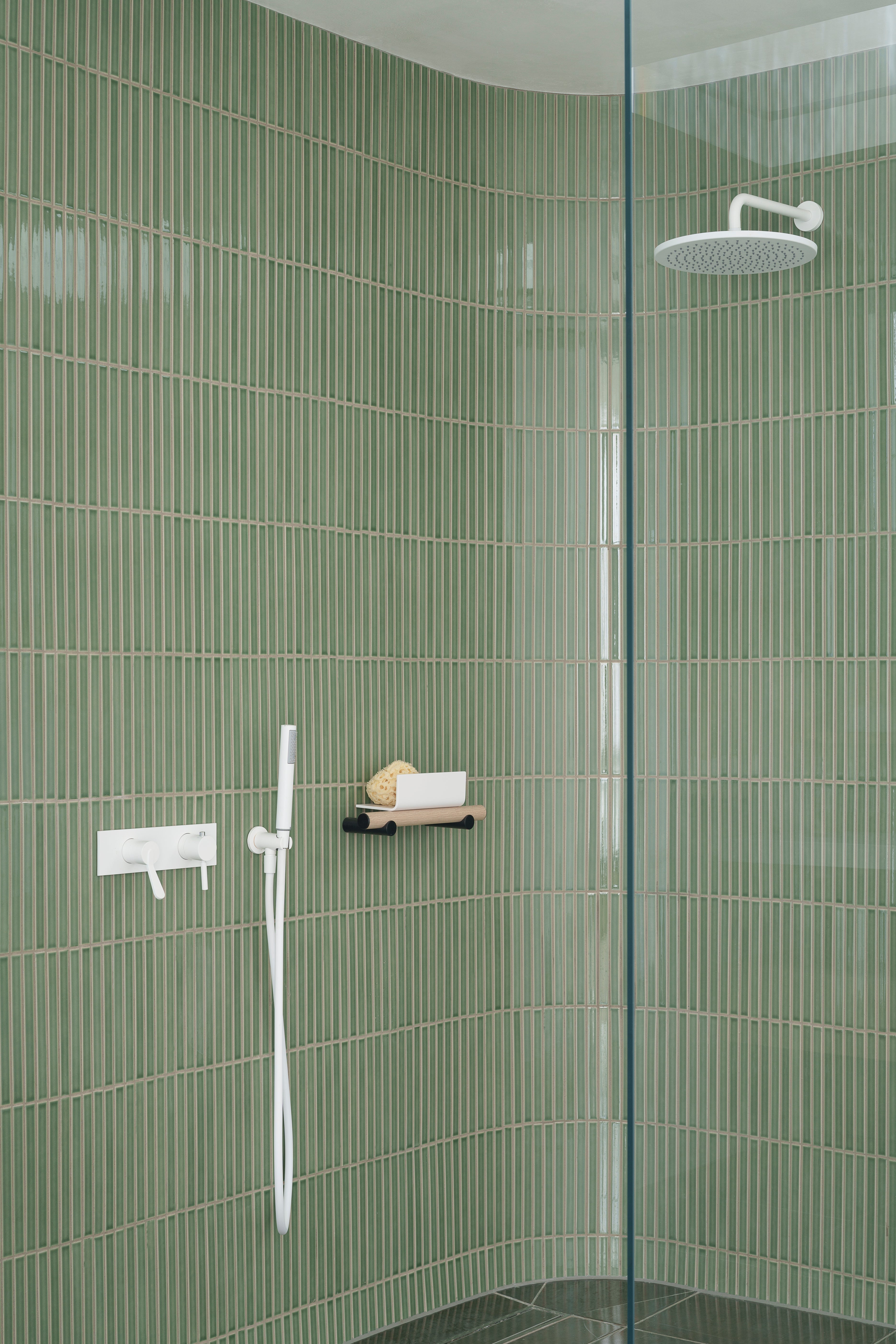 Curved shower lined with Arcaico Green tiles at Hanover Penthouse in Dublin.