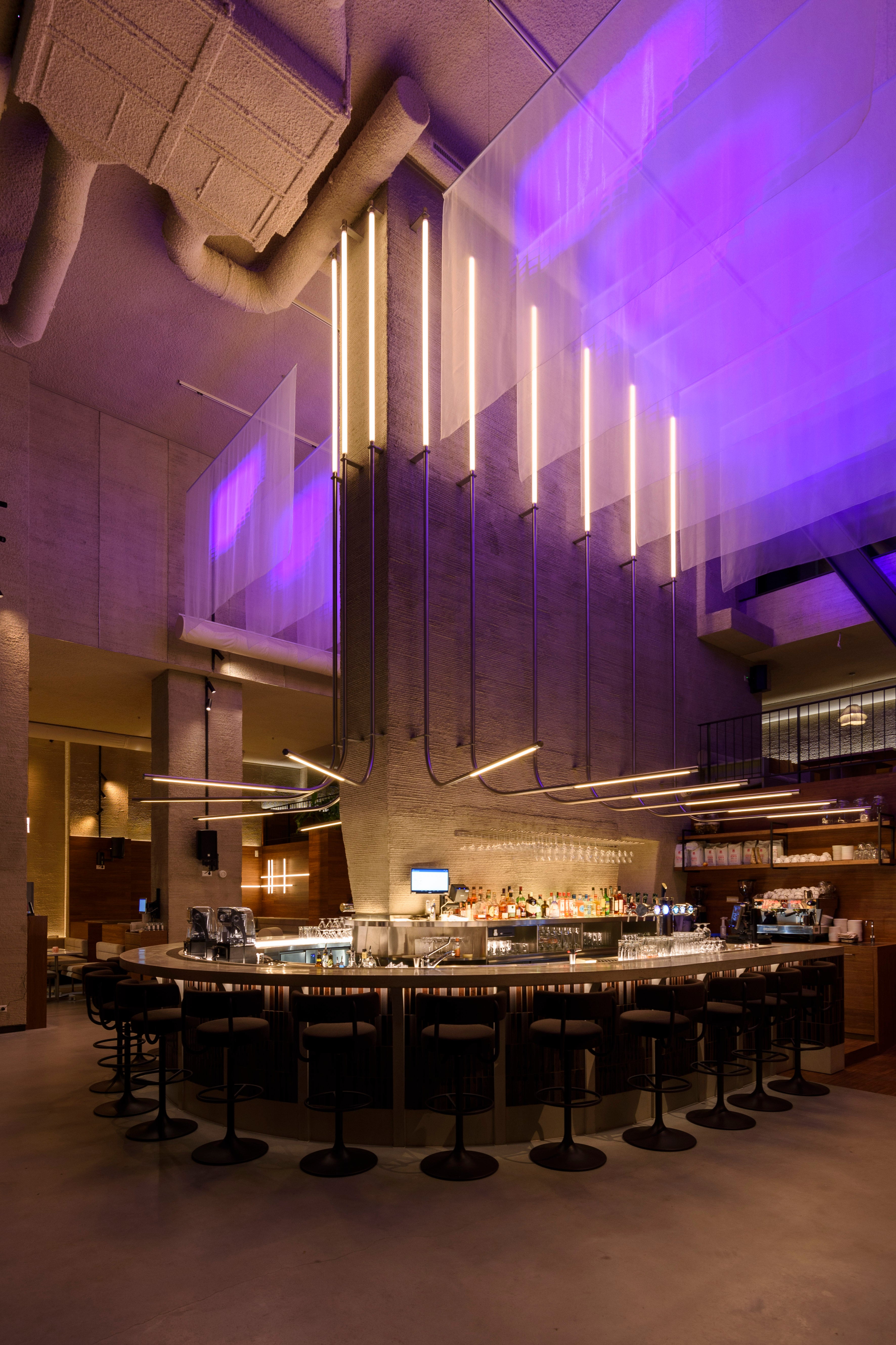 Double-height NEXT Amsterdam interior with the central bar clad in Sairin Brown Mix.