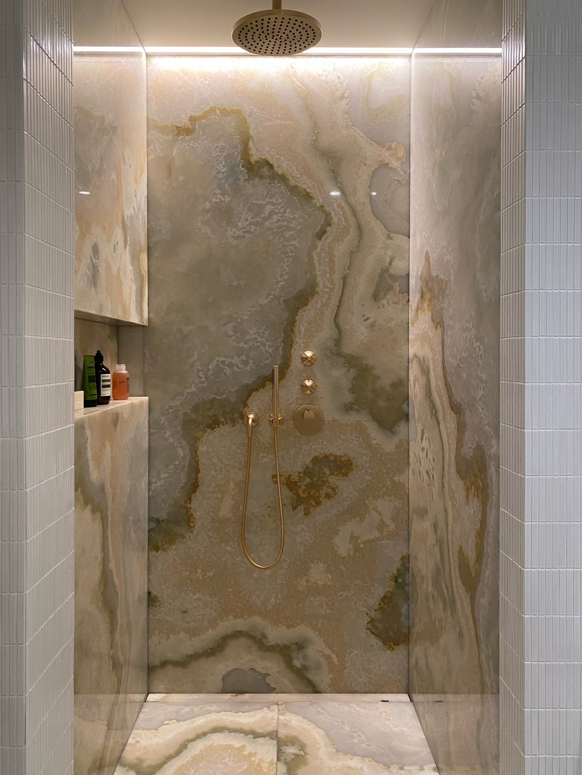 Shower in a private Latvian home with Yohen White tiles and illuminated natural stone.