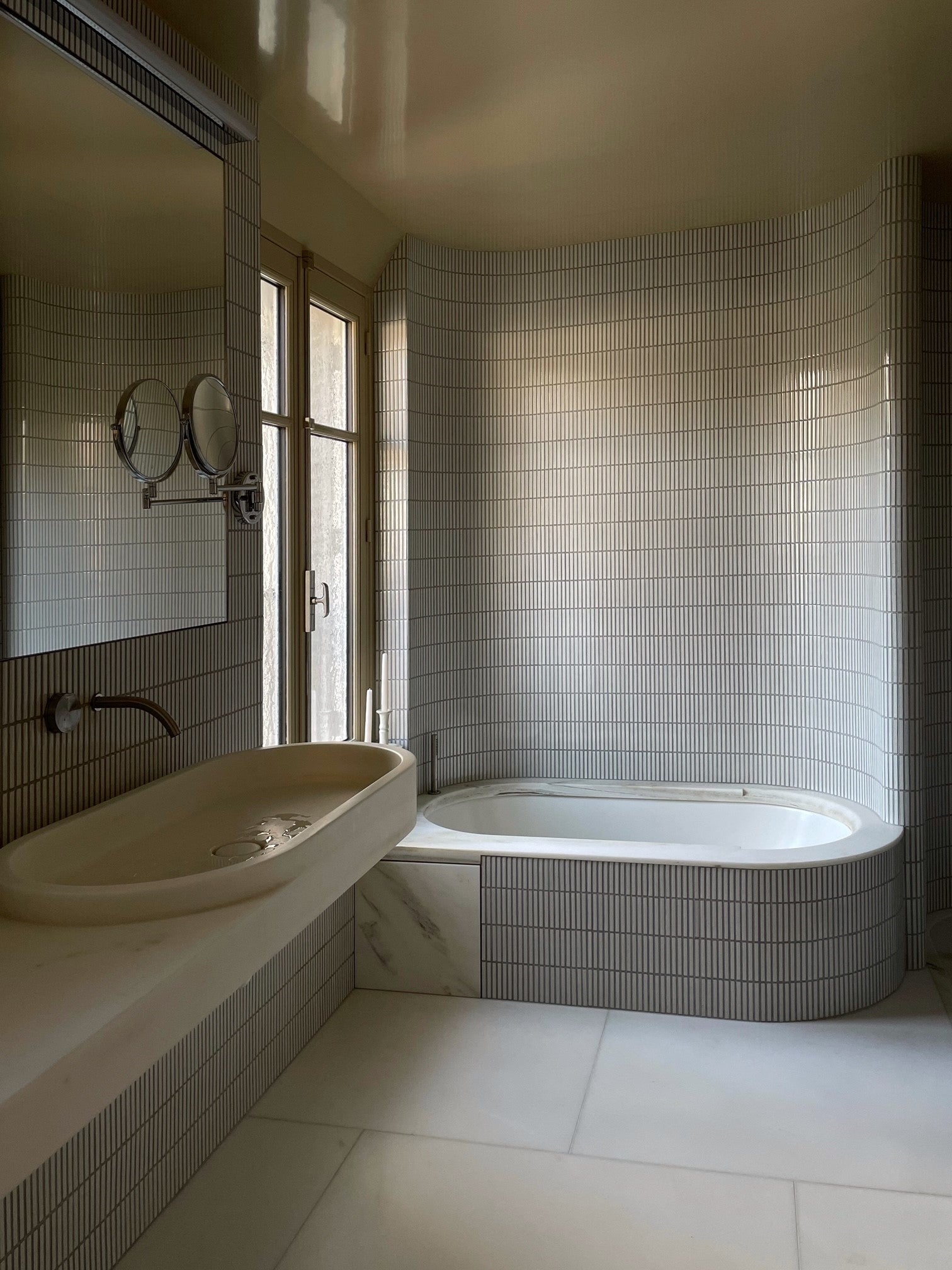 Full interior view of a Paris bathroom lined with Yohen Speckled White Japanese tiles.