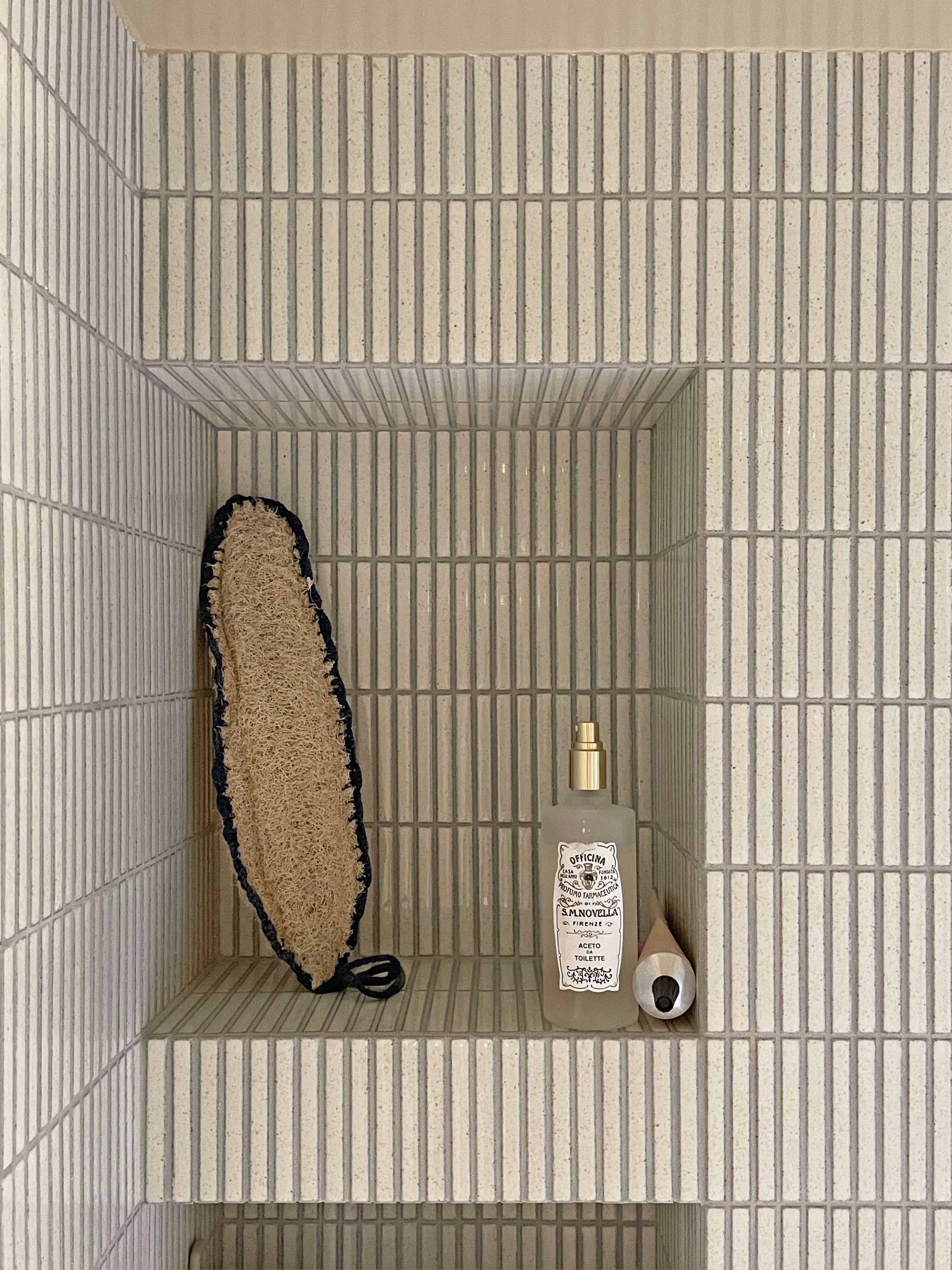 Recessed bathroom shelf precisely aligned with full Yohen Speckled White tiles.
