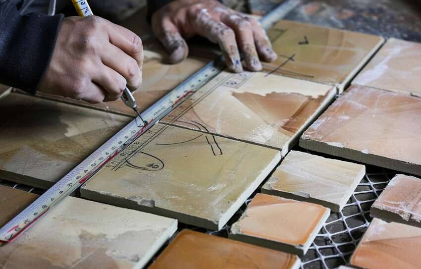 Hands carefully arranging tile pieces in a workshop